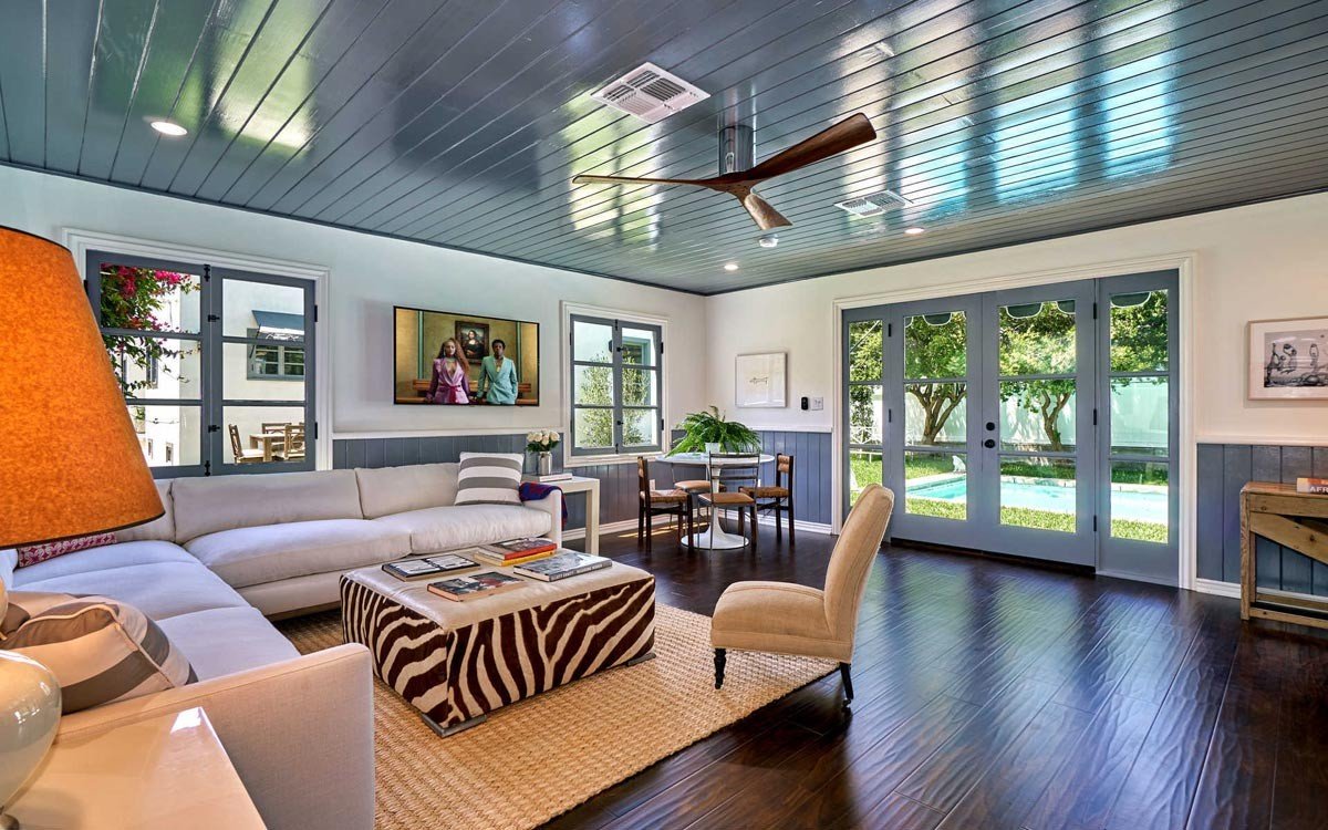 Finished guesthouse living room with dark wood flooring and pool-facing French doors