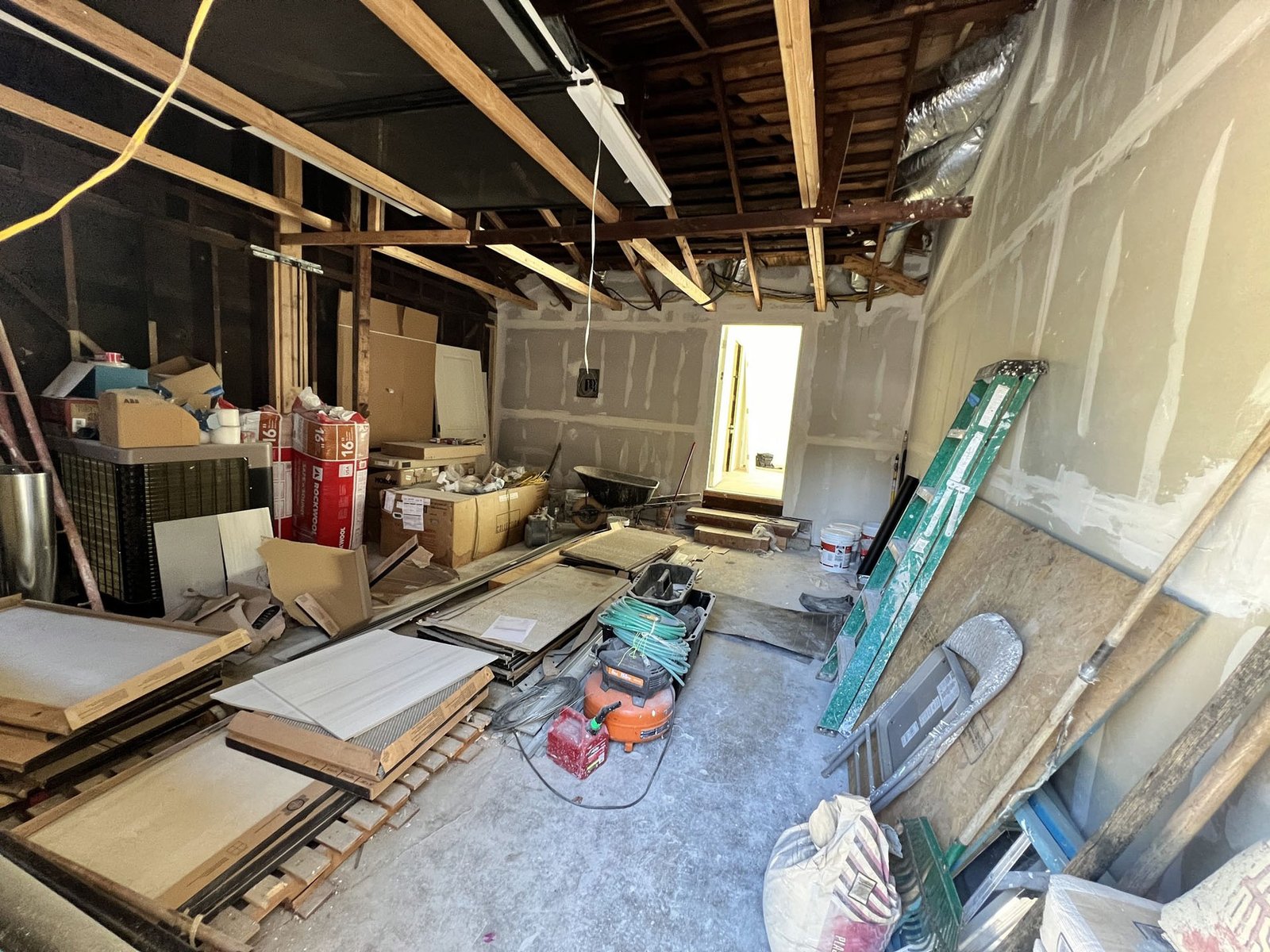 Garage conversion in progress with exposed ceiling framing and building materials