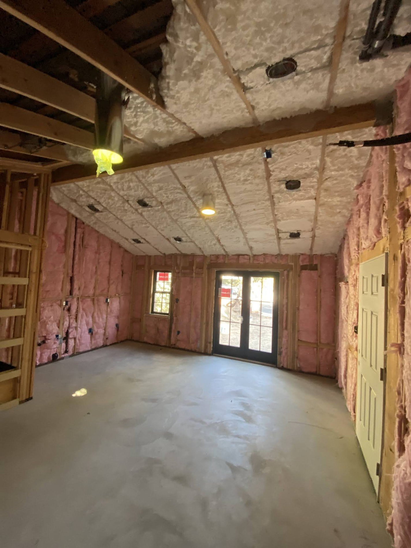 Insulated ADU interior showing recessed lighting and utility rough-in before drywall